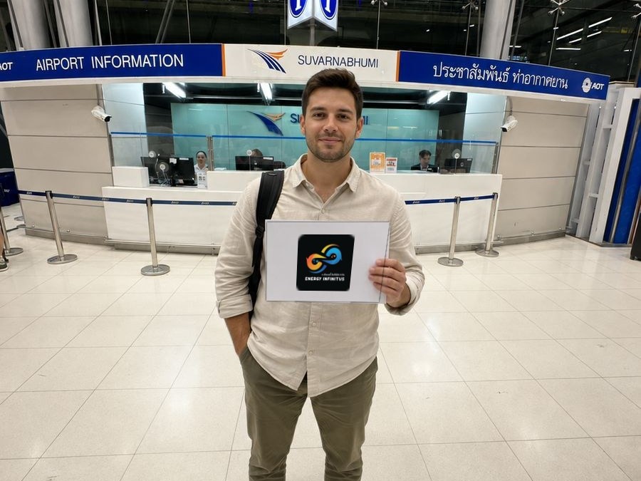 A traveller holding up the Energy Infinitus name board at the Suvarnabhumi airport information counter